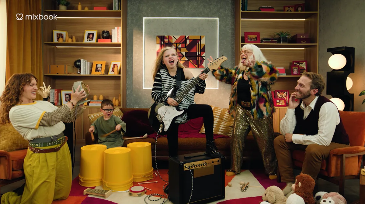 Quinn Newman performing with a guitar alongside the cast in a Mixbook commercial