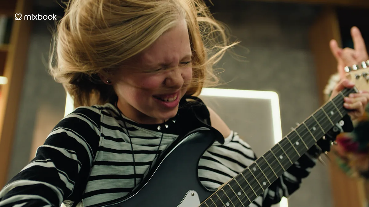 Quinn Newman smiling with a guitar in a Mixbook commercial